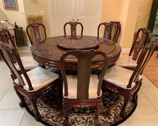 Oriental teakwood dining table and 8 side chairs. 20/21 C. Custom made with Mother-of-pearl inlay and center Lazy-Susan. In the "Ming" style, the chairs with pad cushion seats. $1500