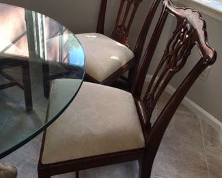 Glass top table with ornate base with four matching chairs.