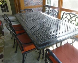 Large (86" x 42") cast metal table and 8 armed chairs. End chairs are swivel with rust colored fabric seats, 6 side chairs are armed (4 with matching rust colored fabric, 2 with cream colored fabric seats.)