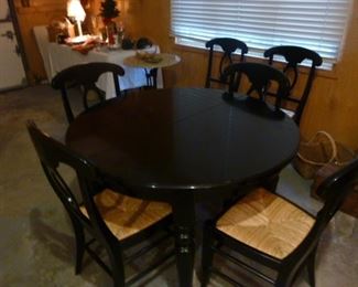 Black round table with two leaves and six rush seat chairs in very excellent condition!