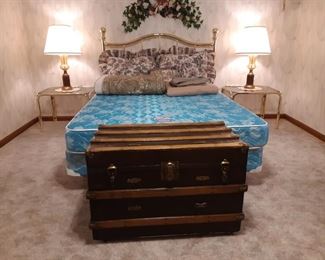 Brass Queen bed in the basement with set of glass and brass side tables 
