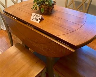 Lot 3382  $425.00. Very Cool Round Dinette Drop Leaf Table with 2 Lower Shelves and 4 Attractive Chairs w/ Wood Seats and XX Pattern on Back of Chairs. Greenish Gray 	Table: 41" Diameter 20" W x 41" L as Drop Leaf, Chairs: 17" D x 18" W x 17.5 H, 35.5" H to Back of Chair 	