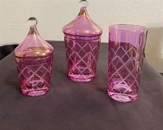 Beautiful pink glass vanity set in mint condition. No markings and not sure of the age but at least 60 years old. (3) pieces that are cut glass, two have the lids and one heavy drinking glass. $30