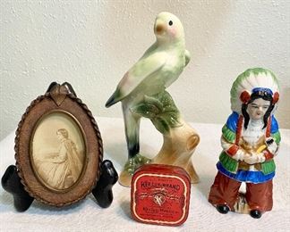 Group of collectibles - Ceramic parrot with great color, measures 8" tall, very old leather & copper frame with lady picture, ribbon tin "Keelox", and ceramic Indian statue, measures 6" tall, marked on bottom "Made in Occuipied Japan." (Lot of 4)  $24