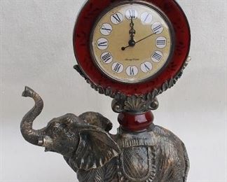 $95 Cast resin African elephant supporting an ornate clock w/ Roman numerals & 3 hands; appears as cast metal & burgundy enamel.  L: 9.5" | H: 16" | D: 4.5" | clock face diameter: 4" [Props] 