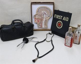 $50  LOT Clockwise from left: Vintage Gladstone bag, leather or embossed leatherette.  L: 16" | W: 7" | H: 9"
- Cutaway model of human head, in box.  Made in India.  W: 10" | H: 13" | D: 2"
- Vintage Red Cross first aid kit, metal box containing original boxed bandages.   W: 9" | H: 9.5" | D: 3"
- Vintage corked medicine bottles.  W: 3" | H: 9" | D: 2" | 1 pt.? 
- Vintage stethoscope, metal & rubber.  L: 20"  
- Vintage forceps (obstetric?), metal & rubber.  L: 10" | W: 5" [Bin 33] 
