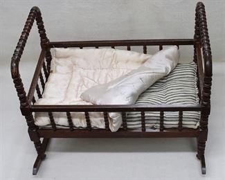 $45 Vintage doll's cradle of dark wood w/ turned spindles, slat bottom, blue-striped mattress, pale pink satin comforter.  L: 22" | W: 13" | H: 17.5" | rockers: 19" [Bin 32b] 