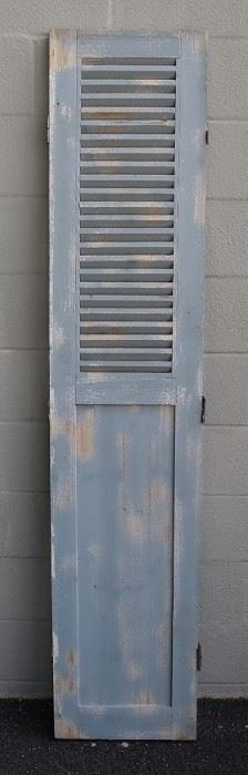 $75 - Wood shutter, grey distressed finish, stationary louvers on upper half, 3 brass hinges each side, slides on bottom.  W: 16" | H: 75" | D: 1" [Props] 