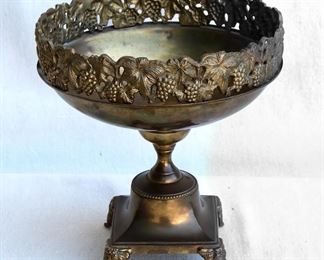 $30 - Brass fruit bowl, rim and feet of cast grapevines, pedestal base 5.25" square at bottom.  W: 9.5" | H: 10.25" | D: 9.5" [Props] 