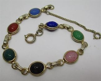 A costume jewelry bracelet set with multiple colored glass stones in the link.  Stones are impressed with stylized scarab pattern