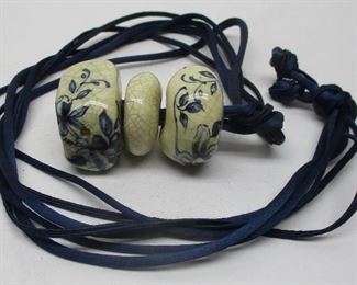 Three Chinese blue & white crackle glaze beads on black silk string.  Approximately 1 inch wide beads