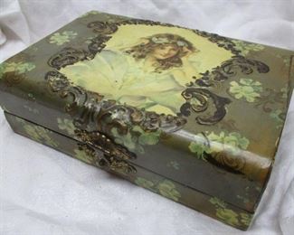 A late 1800s celluloid covered box fitted for a manicure set.  Stone litho image of a woman on the lid.  On corner loose