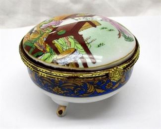 A porcelain footed trinket/jewelry box.  Transfer pattern of Japanese women artist painting a scroll.  Mirror in inside of lid.  3" diameter