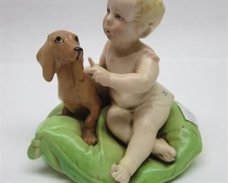 Vintage porcelain figurine of a child and dachshund dog seated on a cushion.  4" tall.  Numbered 840 on the base.  Unsigned, made in the style of G Calle
