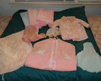 Vintage children's clothing & blankets; pink kitten item $7; blue knit item on right is $6; pink bonnet and pink coat set $18;  3 receiving blankets $12; pink bonnet $5; lace item on left $7