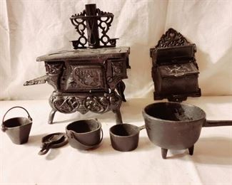 Miniature cast iron antique stove, also known as a salemans sample. With a Vemus and Cupid match holder and cookware.