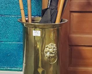 Antique brass umbrella stand with lions head decoration and assorted canes, umbrellas and primitive walking stick.