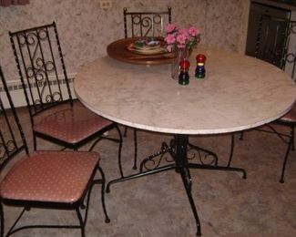 1960'S BLACK IRON ROUND KITCHEN TABLE SET--6 CHAIRS---MIGHT HAVE A LEAF THAT WE HAVEN'T FOUND YET--MADE BY LLOYD CO.----SOME METAL BALLS MISSING ON THE TOP OF SOME OF THE 6 CHAIRS--LIGHT PINK AND GREY LAMINATE TOP