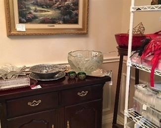 The server has leaves that open on each side.  One of many Thomas Kincaide prints. Serving pieces including a cut glass punch bowl , crystal & pewter pieces. Tall plant stand. 