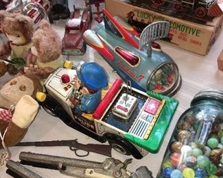 like new tin space toys and windup metal toys and a jar filled to the top with Early marbles