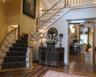 Large console, pair of lamps, floral arrangement. Large oil on canvas decorator art on upper level of staircase.