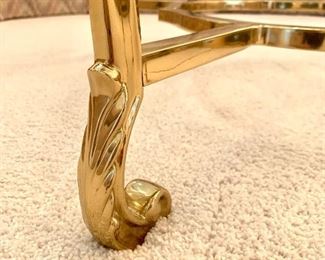 Detail on the legs of the glass top, brass base, coffee table.