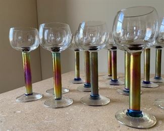 Item 87:  Set of 17 studio art glasses by Steven Maslach (1986). These wine glasses or goblets feature an iridescent stem with gently iridescent bowl and base. - 7":  $395/Set