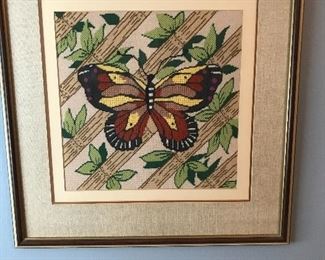 There are several framed needle point pieces