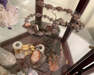 8. Small tabletop curio with jewelry and figureines inside as well as a pair of mother of pearl opera glasses binoculars. Some antique foreign coins as well.    One pin which is a marked piece of 14k Gold (shown with coins) $125 all