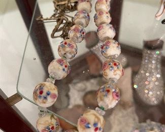 8. Small tabletop curio with jewelry and figureines inside as well as a pair of mother of pearl opera glasses binoculars. Some antique foreign coins as well.    One pin which is a marked piece of 14k Gold (shown with coins) $125 all