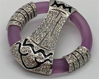 Lovely brooch by Art Deco. Featuring a lovely purple circular brooch detailed with black enamel and rhinestones. Hallmarked on the back, 'Art Deco 89" and the number B054. Measures 2" in diameter. 