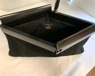 DeVecchi Clutch Envelope Clutch in Black. This wonderful clutch was made in Italy. It has a wooden top and a fabric bottom. It has a very unique open and close design.  This lovely woven clutch was manufactured by De Vecchi of Italy and designed by Hamilton Hodge, who did work for Bottega Veneta, Ferragamo and Donna Karan. This clutch is likely from the early 1990's.  This does have some light wear, however; it is in very good condition. 