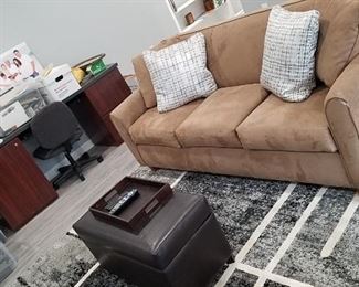 Suede Cloth tan sofa, black, grey, white area rug, black storage hassock, rosewood and black desk