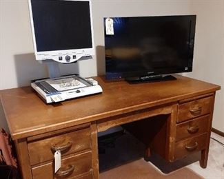 Merlin desktop magnifier; flat screen TV; old wood desk