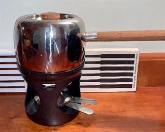Item 233:  A Fondue set in the Suomi Steel Series, Finland, OPA 18/8: $90                                                                                     Designed by Timo Sarpaneva in 1970, teak handle and cover knob, comes with Vintage Stelton of Denmark Fondue Fork Set