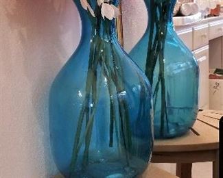 Beautiful turquoise vase sitting on wooden shower bench with a holder for soaps and shampoos etc...