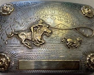 2) $400 Vintage 1955 Sterling Silver and 10K Gold Renalde Trophy Buckle. 123 grams total weight. No name is engraved on the bottom plate but is engraved Blythe Junior Rodeo ALL AROUND COWBOY 1955. Features 4 Roses in corners and Roping Scene.  Stamped Renalde Sterling Silver Denver Colorado 10K. Some scratches as shown. Measures approx 21/2 x 3 3/4 (1 of 2 views) 