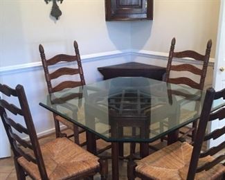 Square glass table top on wood stand with four antique ladderback chairs.
