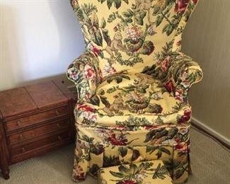 Armchair upholstered with yellow monkey print fabric and matching footstool.
