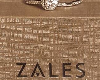 https://ctbids.com/#!/description/share/685481 10K white gold bridal set from Zales. Center stone approximately the same size as a 1 carat diamond. Wedding band curves slightly to fit beautifully against the engagment ring. Accent stones register as diamonds using the HDE Diamond Selector II diamond tester. Center stone does not register as a diamond. Like new. Size 7. Includes Zales box. If a center diamond is preferred, simply swap out the center stone and keep the setting.

