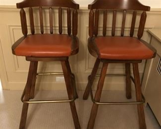 Set of four swivel bar stools with leather upholstered seats and brass foot rests.