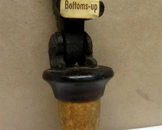 A vintage Italian Anri Scottie dog figurative wine bottle cork.  Dog figure stands up and is holding a bottoms up sign.  4.75" tall
