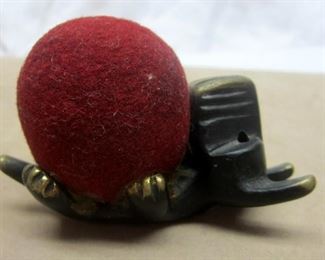 A Japanese cast iron mid-century Scottie dog figure, holding a felt ball glued on to its' paws.  Likely for use as a pin cushion.  3" long

