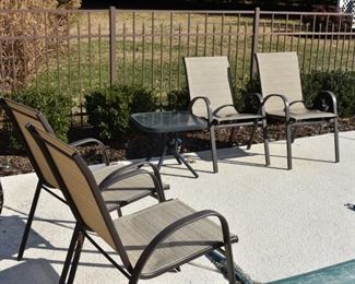 Outdoor Chairs and Glass Topped End Tables around the Pool