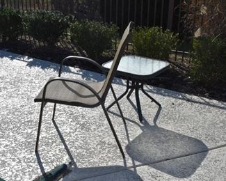 Outdoor Chairs and Glass Topped End Tables around the Pool