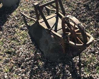 Vintage wheelbarrow with metal wheels and wooden handles.
