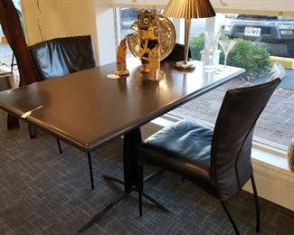 Corian top iron base table shown with four Dutch  Montis Furniture Co. black leather upholstered side chairs 