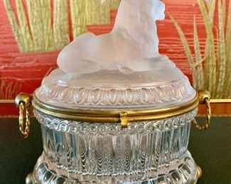 $250; Oval crystal trinket box with frosted lion figural top, brass ornaments and base; Approx 8” H x 7” W x 5” D.