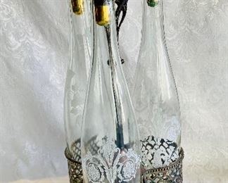 $75 - Three, Etched Bottle Set with Silver Plated Holder; holder is 16" H x 8" W 