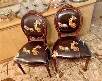 $395 - Four Cherub and Chariot Dining Chairs. As is, tears and cracks to the vinyl coated upholstery fabric; 37.5" H x 21" W x 21" D, seat height is approximately 19"